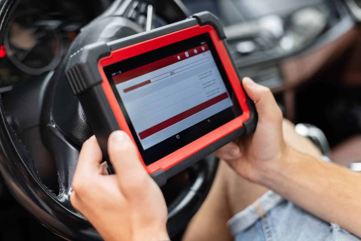 Mechaniker mit digitalem Diagnosegerät in einer modernen Werkstatt